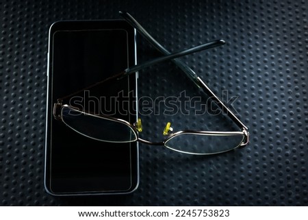Reading glasses on a mobile phone on a black background