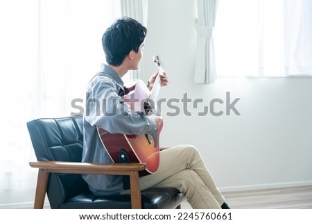 Young man playing acoustic guitar Royalty-Free Stock Photo #2245760661