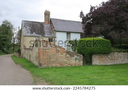 An old house in rural England with a brick wall saying "the lime house".  It is surrounded by a pathway and grass.  Image has copy space.