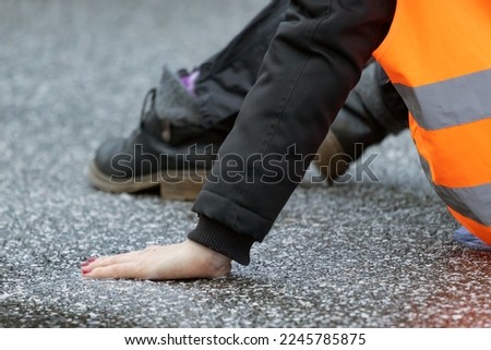 a climate activist glued herself to the asphalt with superglue Royalty-Free Stock Photo #2245785875
