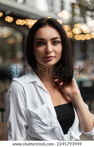 Fashion beauty portrait of beautiful woman with bob hairstyle in stylish white shirt on the street with light bokeh