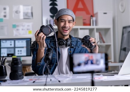 Young Asian man graphic designer blogger influencer filming teaching camera tutorial while looking at camera shooting education tutorial vlog training filming video course for social media at studio. Royalty-Free Stock Photo #2245819277