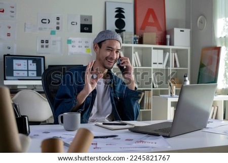 Asian man Graphic designer talking on mobile phone while working in office. Artist Creative Designer Illustrator Graphic Skill Concept.