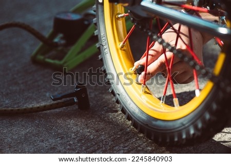 Pump up the bicycle tire with pump. Inflate the tire. 