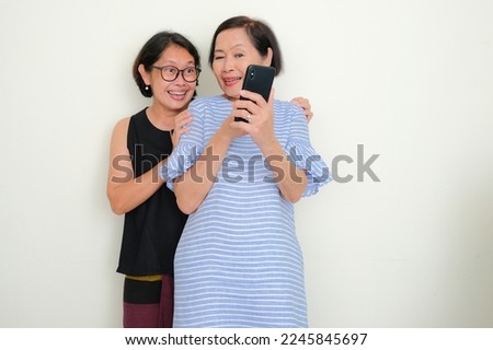 Two women standing and making a video call together Royalty-Free Stock Photo #2245845697