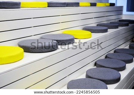 Yellow and gray soft seats on white wooden steps in the event space. The concept of training seminars and trainings. Horizontal photo