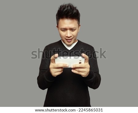 Handsome man is holding mobile phone with happy expression and smiling
