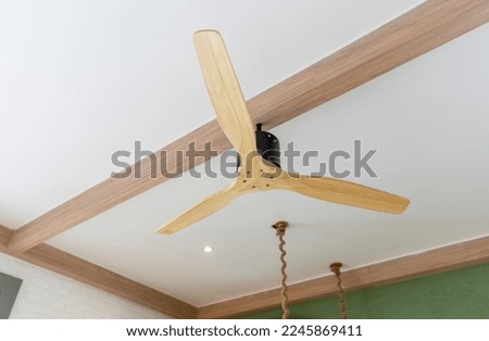 Wooden electric ceiling fan under a timbered ceiling.