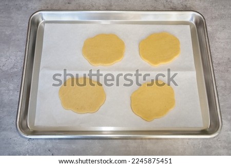 Rolled sugar cookie dough and cut into frame or plaque shape on a cookie sheet lined with parchment paper ready to be baked.
