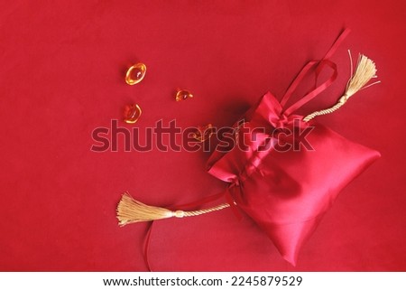 Chinese New Year, red silk pocket money bag with gold ingot on red background, lucky item oriental Asian style with space copy. Royalty-Free Stock Photo #2245879529