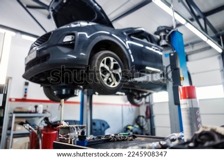 Blurred picture of a car in a mechanic's shop on lift.