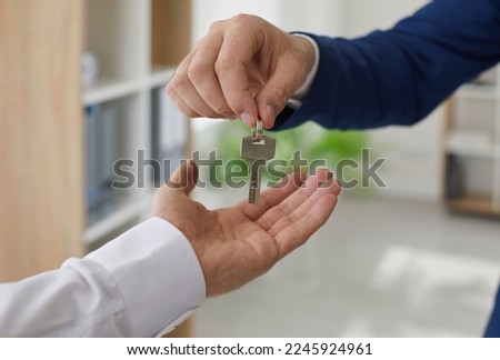 Realtor handing over the keys to a new home owner. Real estate agent gives the key to the buyer. Young man takes keys to his newly bought house or apartment. Cropped close up shot. Real estate concept Royalty-Free Stock Photo #2245924961