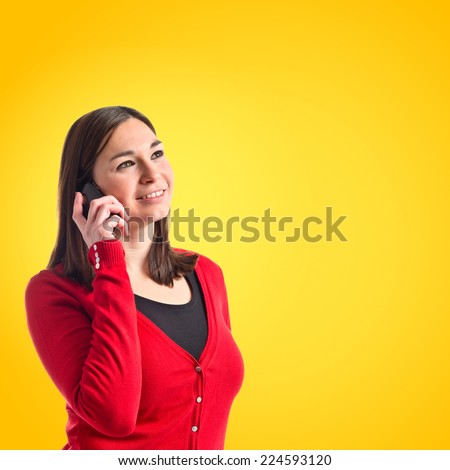 Young girl talking on mobile over yellow background 