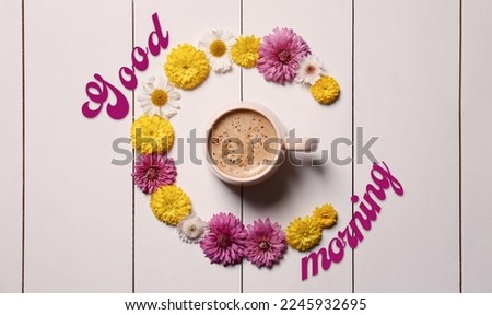 Good morning! Beautiful floral composition with cup of hot coffee on white wooden background, flat lay