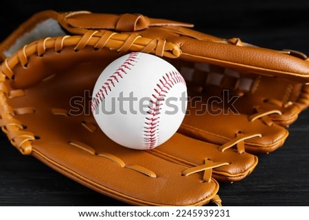 Catcher's mitt and baseball ball on black background, closeup. Sports game