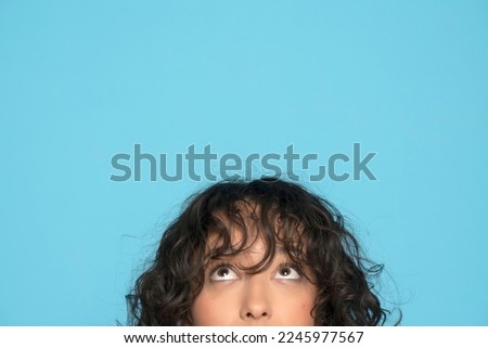 closeup portrait headshot cropped face above lips of cute happy woman looking up isolated on blue studio wall background with copy space above head. Royalty-Free Stock Photo #2245977567