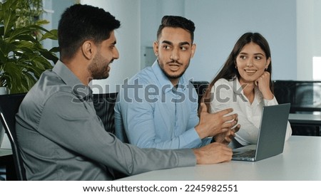 Multiethnic business team three office workers managers discus project online crypto currency brainstorm with laptop computer at workplace. Multiracial coworkers group talk about corporate software Royalty-Free Stock Photo #2245982551