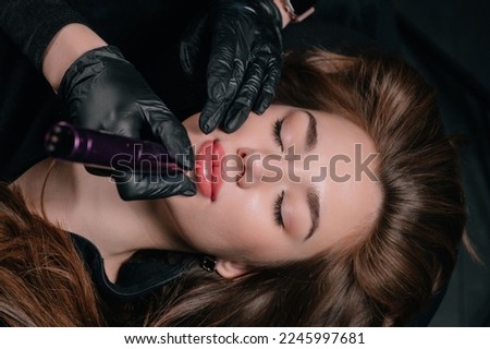 Permanent lip makeup. The cosmetologist makes the procedure of permanent makeup to the client in the salon. Royalty-Free Stock Photo #2245997681