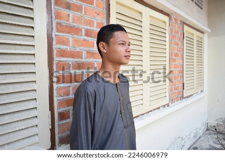 Selective Focus of A Muslim Teenager Wearing Green Kurta Isolated With Vintage House Windows, Blurred Background. Eid Celebration 