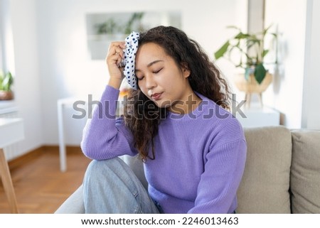 Close-up shot of a Asian woman suffering from a headache cooling her head with a ice pack Royalty-Free Stock Photo #2246013463
