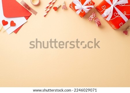 Valentine's Day concept. Top view photo of red gift boxes with white ribbon bows envelope with paper sheet straws hearts decorative tape and clips on isolated pastel beige background with empty space