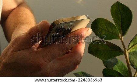 Close up shot of man hands using smart phone for check email for work or sending text SMS short message. Mobile wireless digital technology for communication. Green leaves on the background. Sunlight