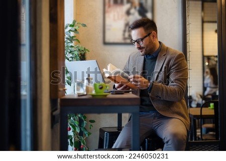 Businessman Reading Book while Sitting in Cafe Royalty-Free Stock Photo #2246050231