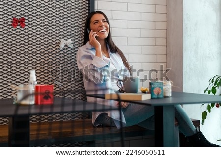 Young woman at cafe drinking coffee and using mobile phone