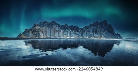 Incredible Iceland nature seascape. Iconic location for landscape photographers and bloggers. Scenic Image of Iceland. Vestrahorn mountaine on Stokksnes cape with Green northern lights and reflection