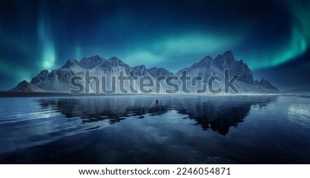 Incredible Iceland nature seascape. Iconic location for landscape photographers and bloggers. Scenic Image of Iceland. Vestrahorn mountaine on Stokksnes cape with Green northern lights and reflection