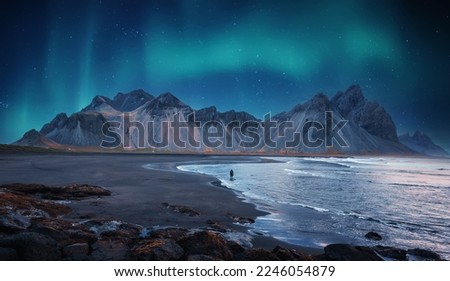 Incredible Iceland nature seascape. Iconic location for landscape photographers and bloggers. Scenic Image of Iceland. Alone tourist against Vestrahorn mountaine with Green northern lights Royalty-Free Stock Photo #2246054879