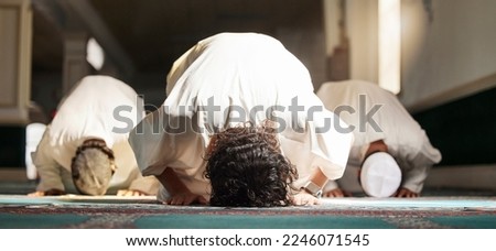 Muslim, prayer and mosque with a spiritual man group praying in faith during fajr, dhuhr or asr, otherwise maghrib or ishaa. Salah, worship and pray with islam men at ramadan for holy tradition Royalty-Free Stock Photo #2246071545