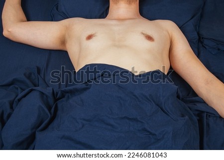 Handsome young man sleeping comfortably on the bed at night in his bedroom without clothes. Bachelor bedroom. Deep sleep