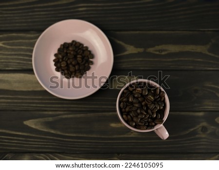 fragrant rich coffee beans of different varieties on a dark wooden surface in a pink coffee cup and saucer. for banners, flyers, splash screens, menu labels