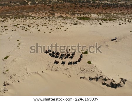 Group of people on a quad bike tour. Adventure tour on the beach with all terrain vehicles. Drone photo from above. People driving on the turle nesting beaches (off season)