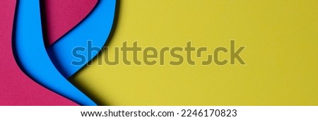 Abstract colored paper texture background. Minimal paper cut style composition with layers of geometric shapes and lines in red and light blue colors on yellow background. Top view