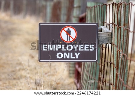 Employees only sign on the farm fence to show restricted access.