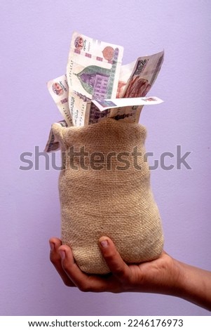 A hand holding a burlap bag with Egyptian money in the denomination of two hundred pounds Royalty-Free Stock Photo #2246176973