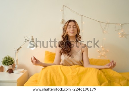 Serene young woman meditating in her bedroom Royalty-Free Stock Photo #2246190179