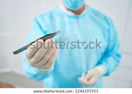Cropped photo of doctor holds in his hand tweezers and a pellet Royalty-Free Stock Photo #2246191955