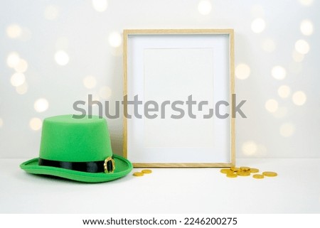 Artwork wall art picture frame product mockup. St Patrick's Day product mockup. Styled with green leprechaun hat and gold coins against a bokeh party lights background. Negative copy space.