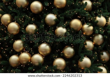 A background of golden baubles hanging on a Christmas tree.
