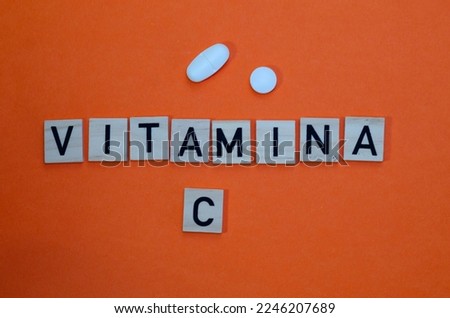Word vitamin c in wooden letters on orange background. Concept of prevention against colds and antioxidant vitamin. Fresh orange slice.