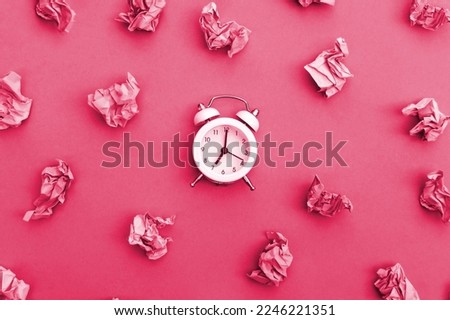 Vintage white alarm clock on a background of crumpled multicolored stickers. Image toned in Viva Magenta, color of the 2023 year