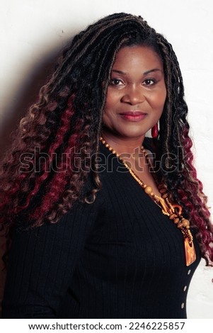 Black mature model with curly crochet braids, smiling, wearing a black top. 