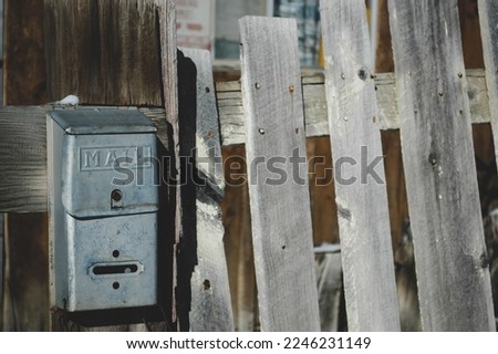 An old metal mailbox attached to a run down wooden fence from an abandoned ghost town in the Colorado Rocky Mountains. Somber and still it sits in its final resting place, untouched for many years.  Royalty-Free Stock Photo #2246231149