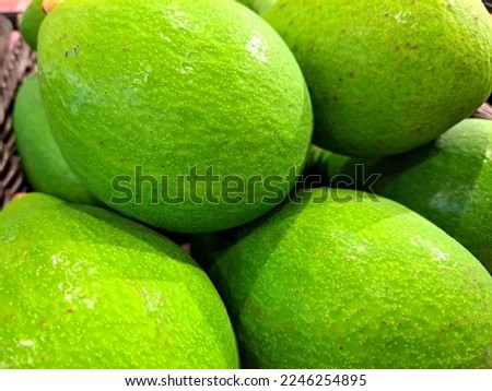 A bunch of ripe avocados with green skin on the fruit shelf in the supermarket ready for sale