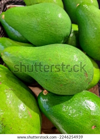 A bunch of ripe avocados with green skin on the fruit shelf in the supermarket ready for sale