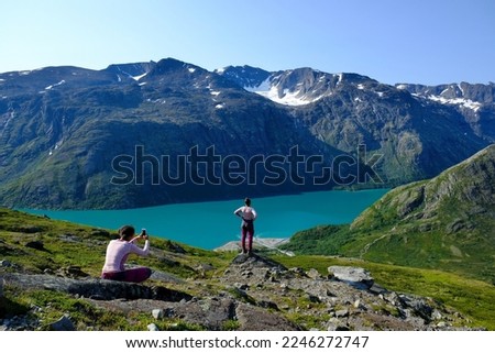 Scenic Besseggen trail with two girl taking photo, in Jotunheimen, Norway - the most beautiful trekking trail in Norway. 