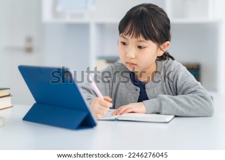 Asian little girl studying with a tablet PC. Royalty-Free Stock Photo #2246276045